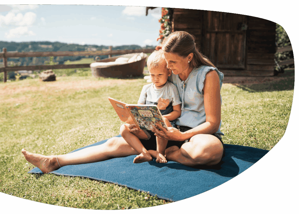 Mama liest Kind vor auf einer Picknickdecke