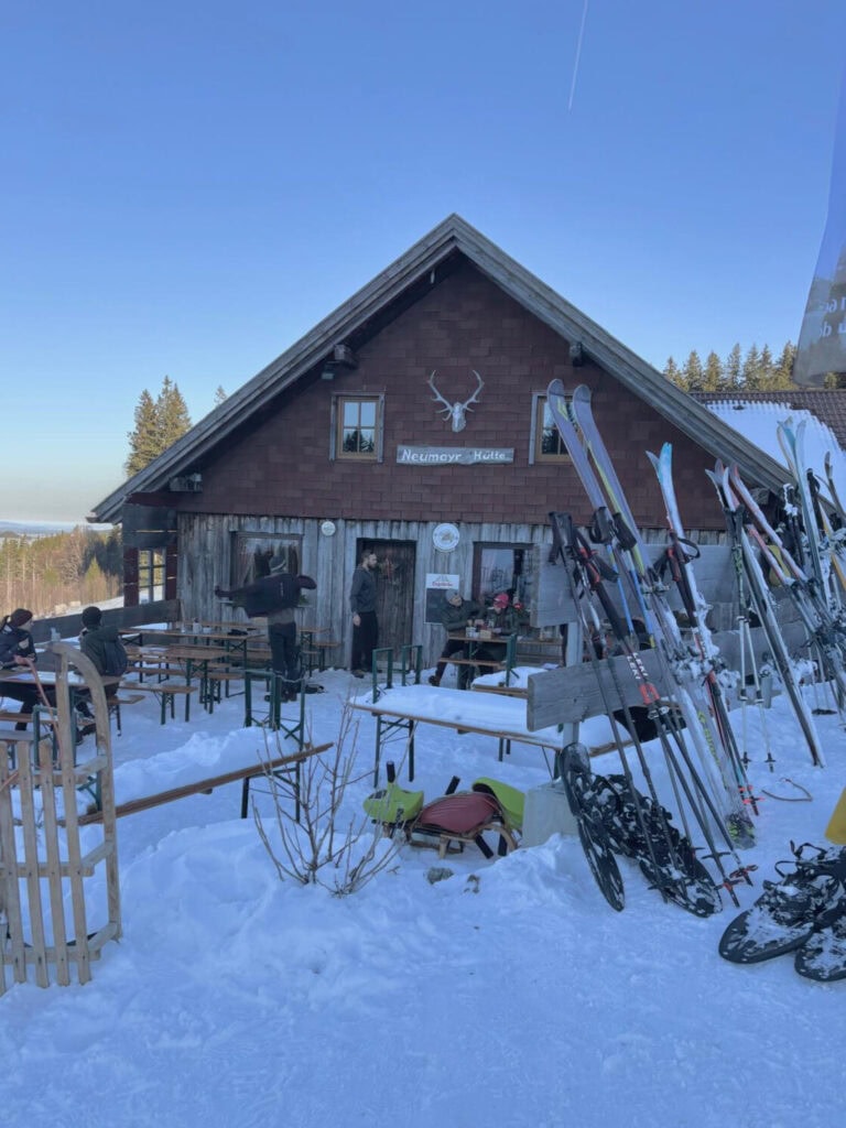 Urige Berghütte im Allgäu, es liegt Schnee und Ski und Schlitten stehen vor der Hütte