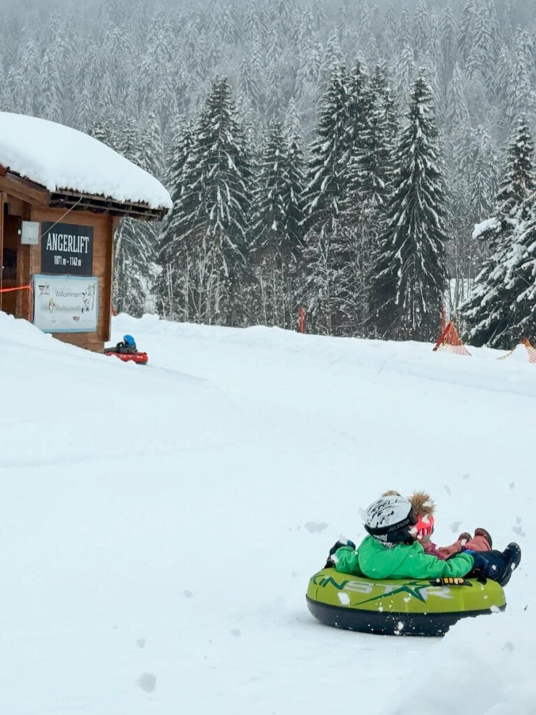 Kind saust auf einem Gummireifen durch den Schnee