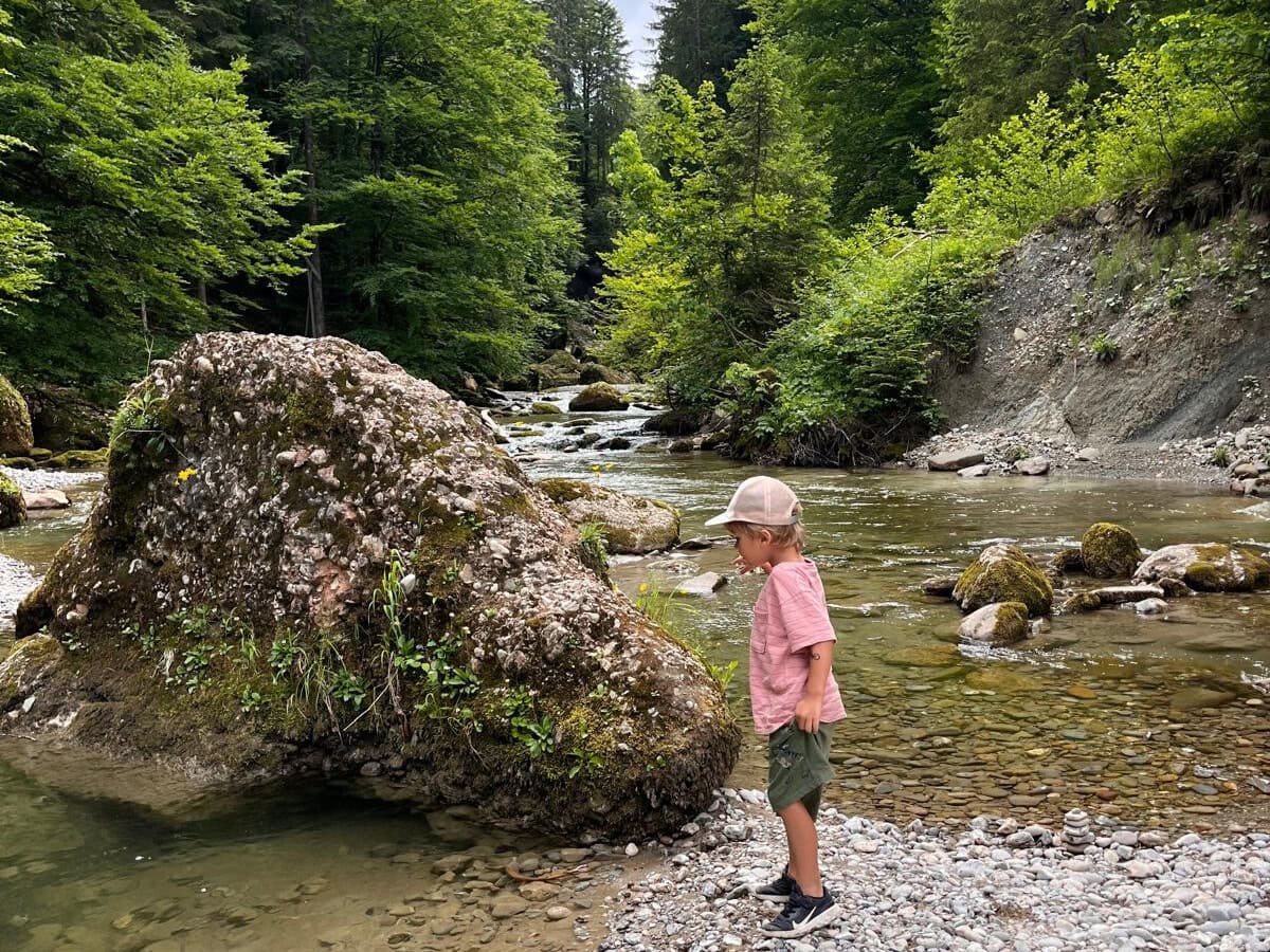 Ein Mädchen steht an einem flachen Gewässer im Haldertobel bei Gunzesried